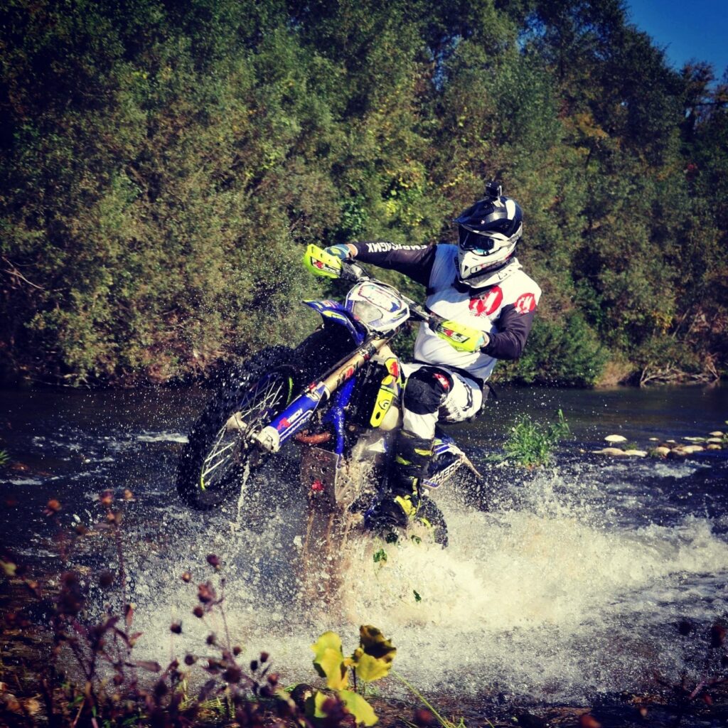 enduro bike doing a wheelie crossing a river