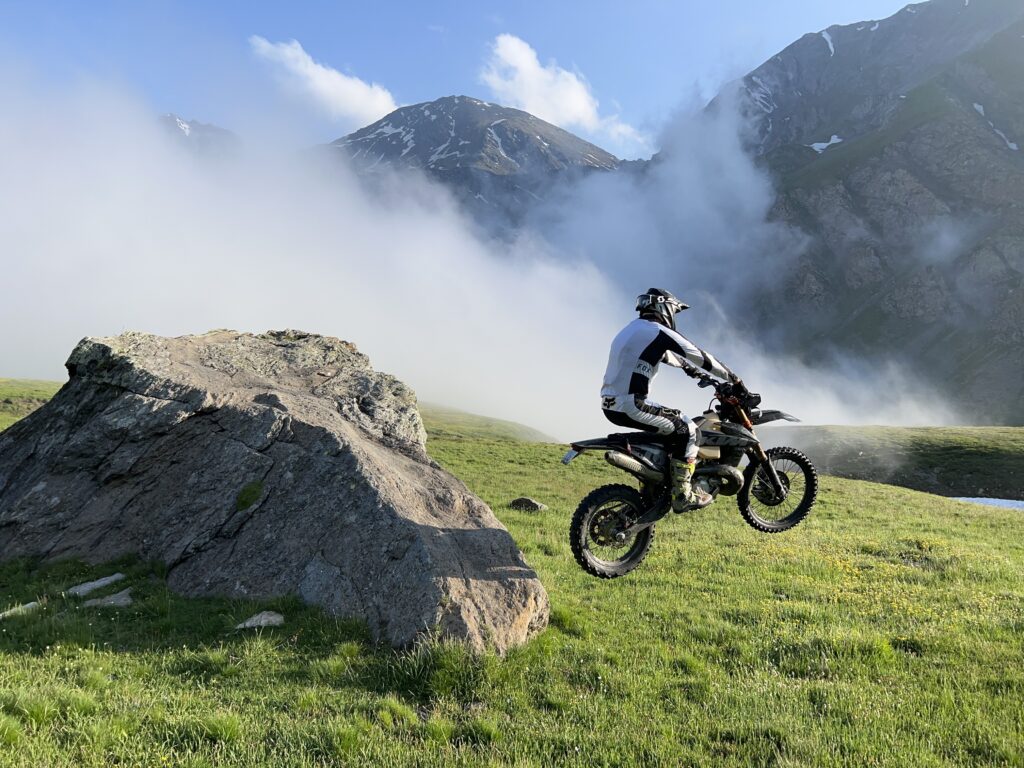 enduro bike over the clouds jumping from a boulder